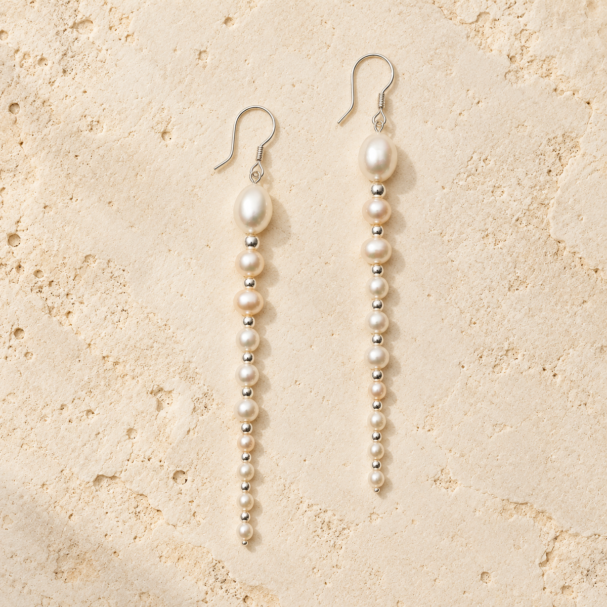 White Ripple pearl drop earrings on warm ivory stone