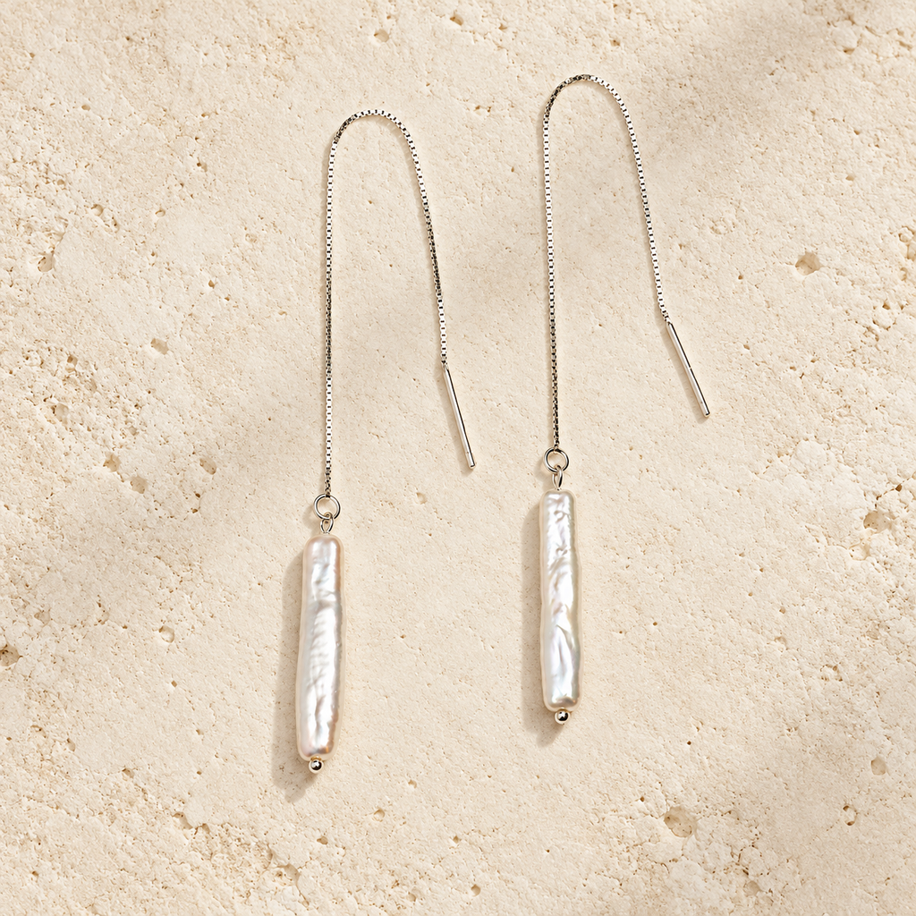 Moon Letter white pearl threader earrings on warm ivory stone