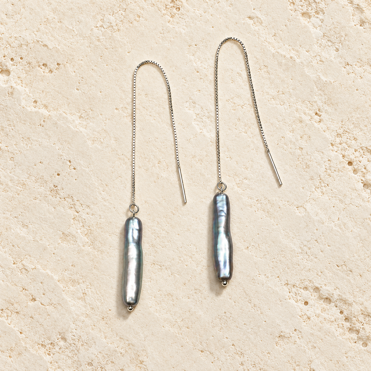 Smoky Veil gray pearl threader earrings on warm ivory stone