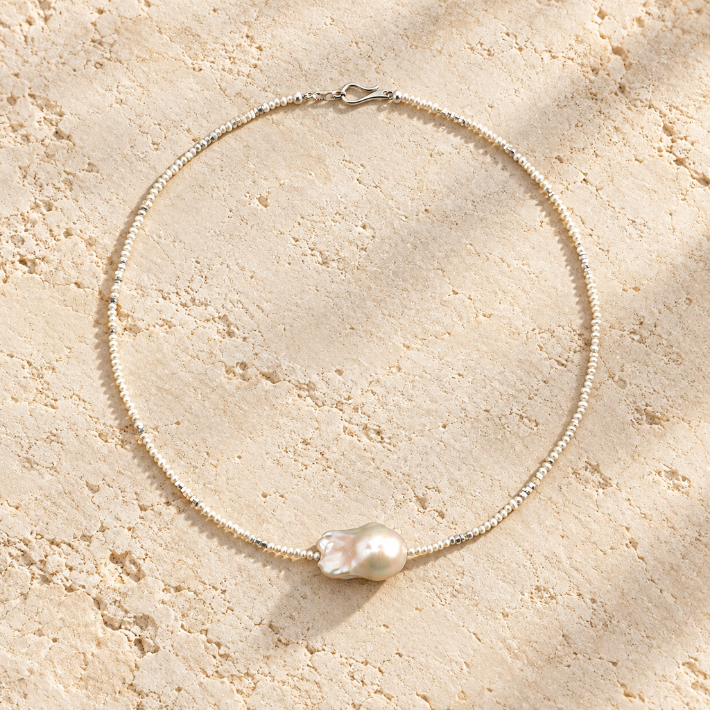 White Tide baroque pearl necklace on warm ivory stone