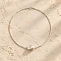White Tide baroque pearl necklace on warm ivory stone