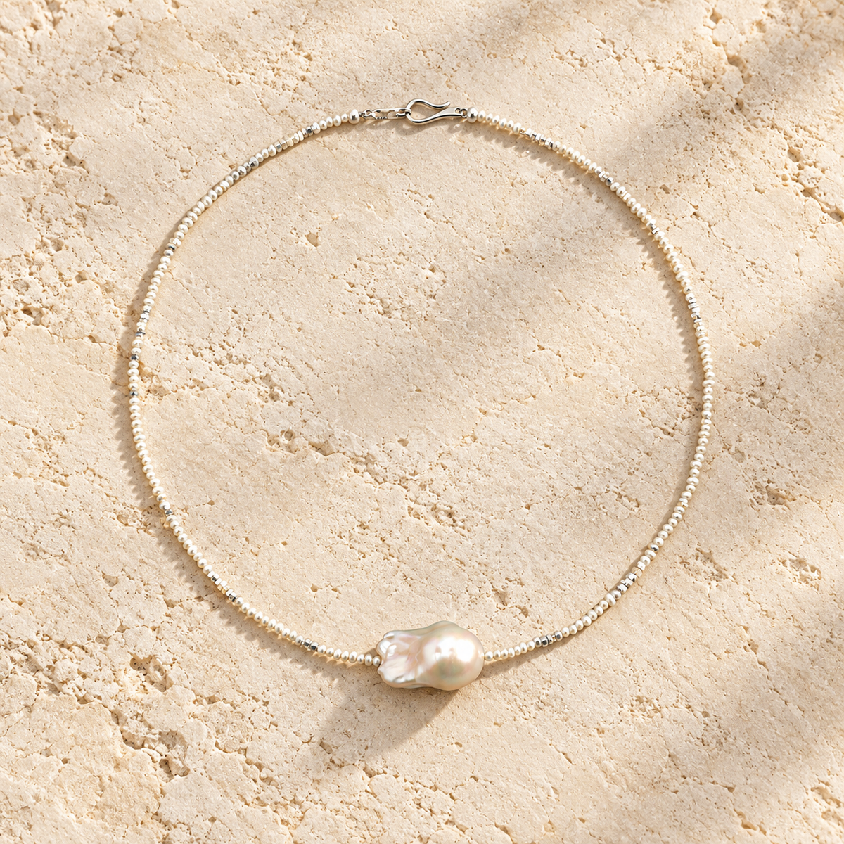 White Tide baroque pearl necklace on warm ivory stone