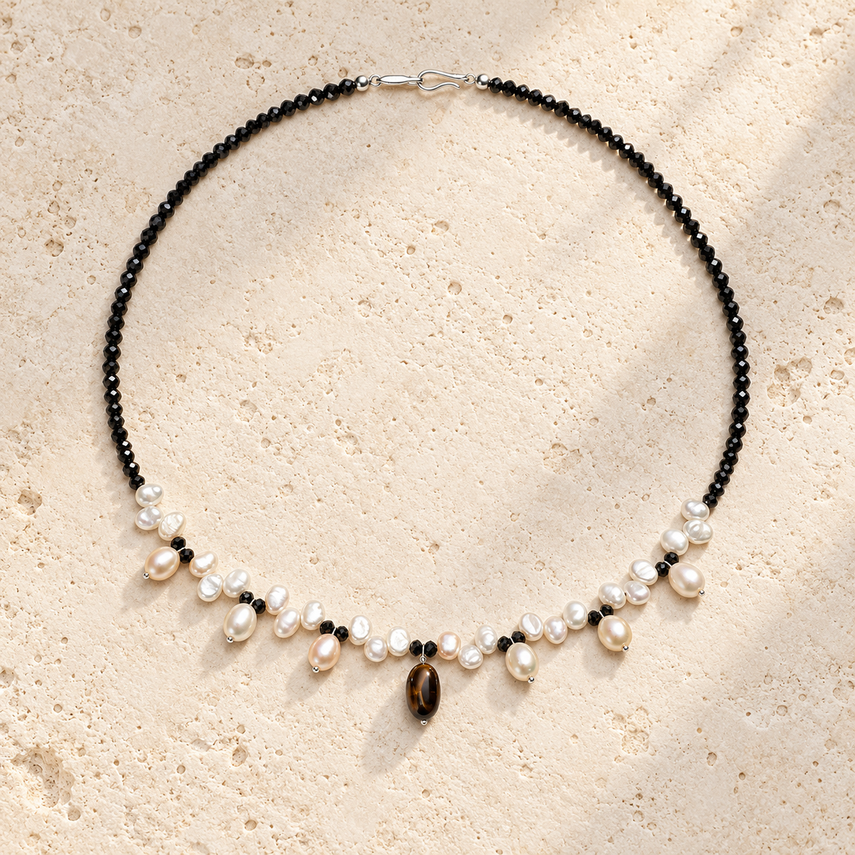 Midnight Ripple pearl tourmaline and tiger eye necklace on warm ivory stone